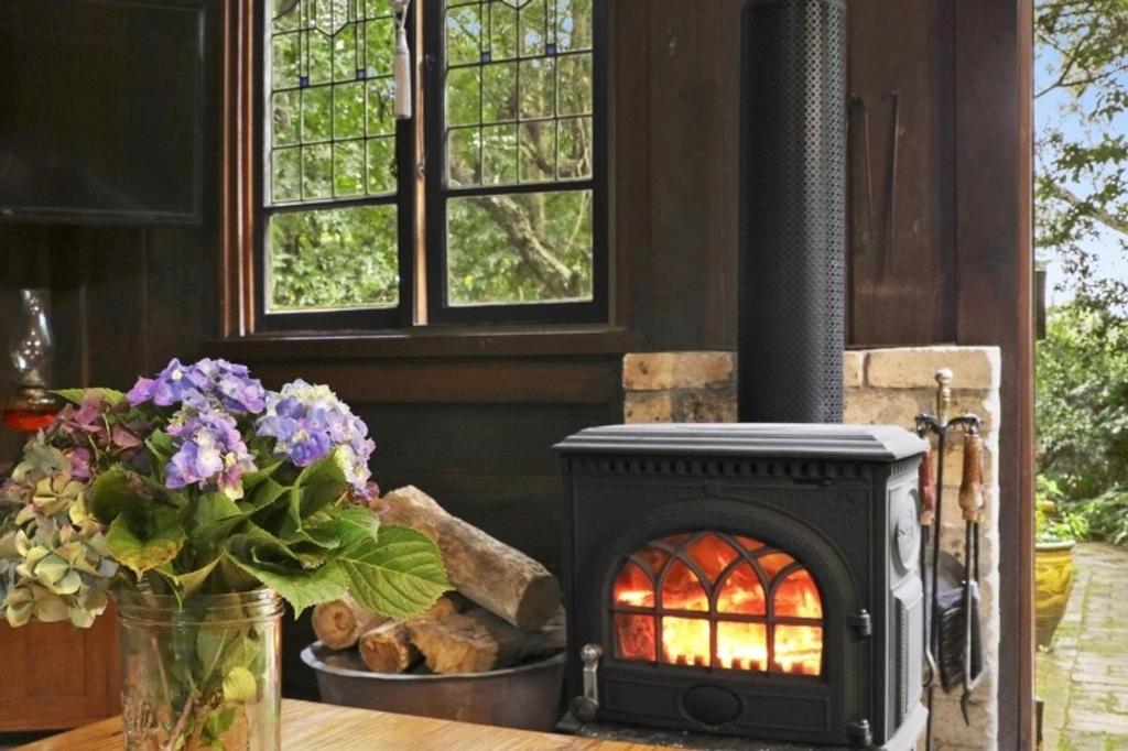 a stove sitting on a table with a vase of flowers at Nungaroo Cottage in Bilpin