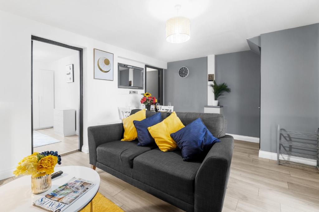 a living room with a couch with yellow and blue pillows at Cosy 2 Bedroom Ground Floor Apartment with Garden - Coventry in Coventry