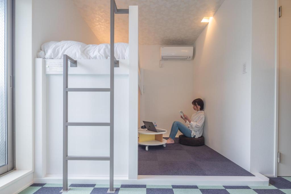 a woman sitting in a room with a bunk bed at Granrina Kanazawa - Female only apartment hotel in Kanazawa