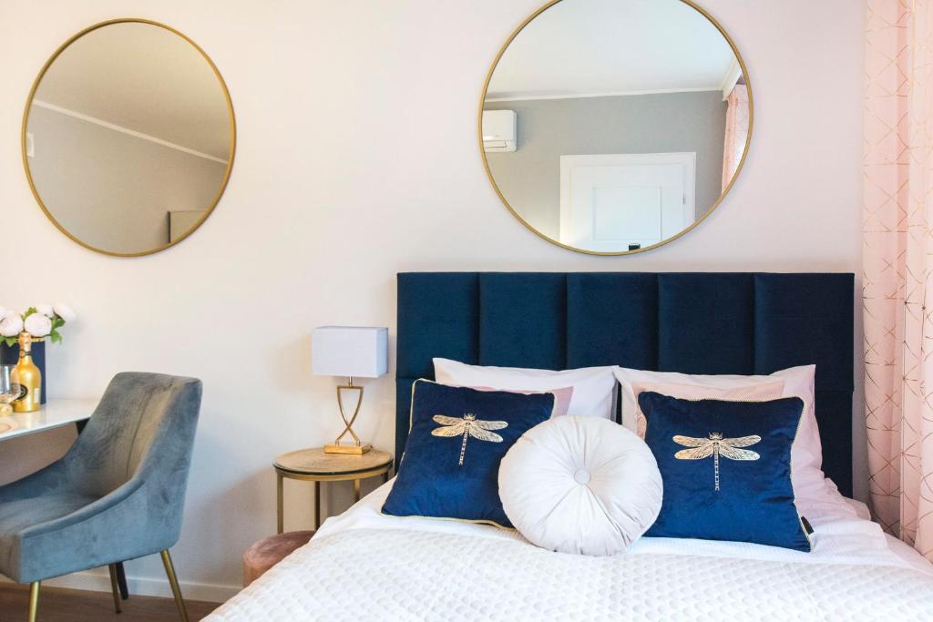a bedroom with a bed with a blue headboard and two mirrors at Śląska 12 by Perfect Apart in Gdańsk