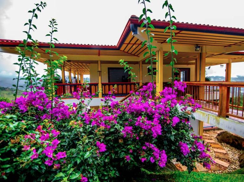une maison avec des fleurs roses devant elle dans l'établissement Hotel Hacienda San Isidro, à Belén de Umbría
