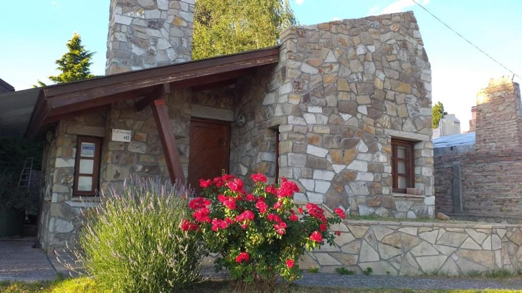 ein Steinhaus mit roten Blumen davor in der Unterkunft Filippo in Zapala