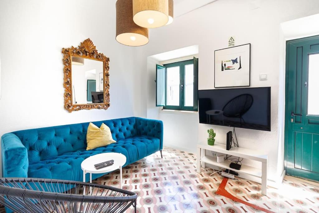 a living room with a blue couch and a mirror at Casa Levante in Sagres