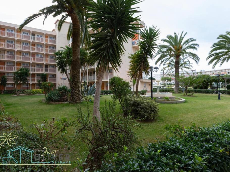 um parque com palmeiras em frente a um edifício em Just Oliver Holidays - Paradis Playa Seafront em La Pineda