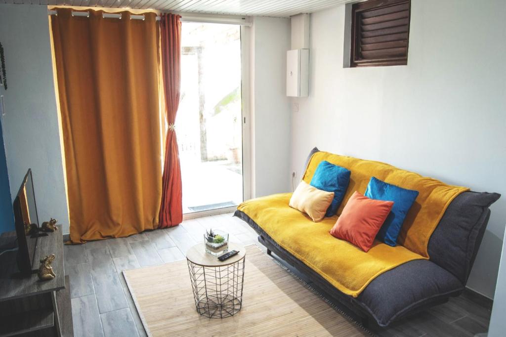 een woonkamer met een bank en kleurrijke kussens bij Bélya in Le Vauclin
