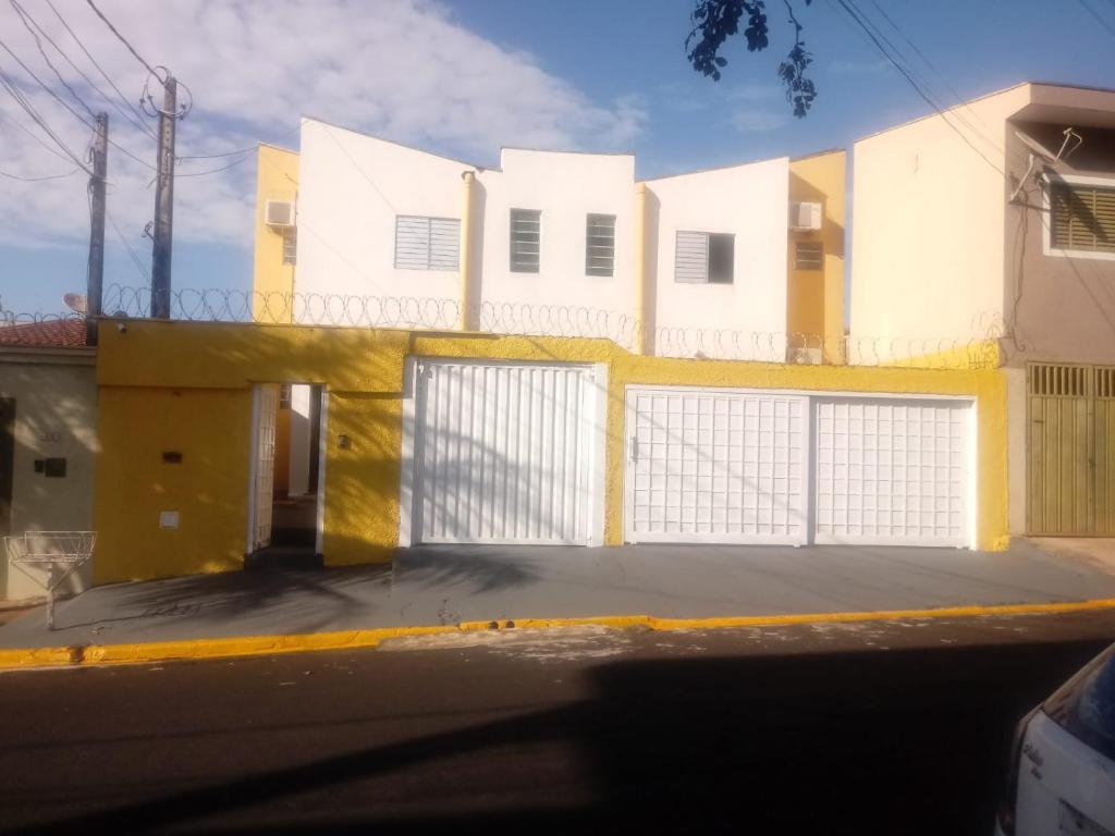 um edifício branco e amarelo com um portão em Hostel Araucaria em Ribeirão Preto