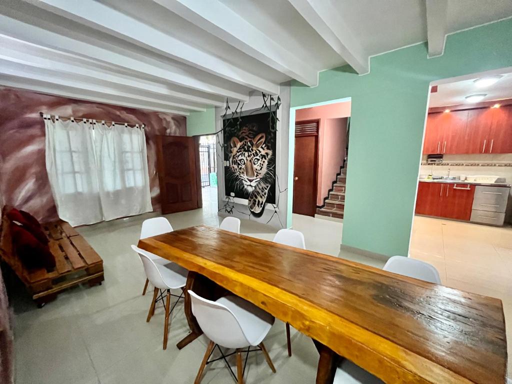 Hostal Casa Macondo في سانتا مارتا: غرفة طعام مع طاولة خشبية وكراسي بيضاء