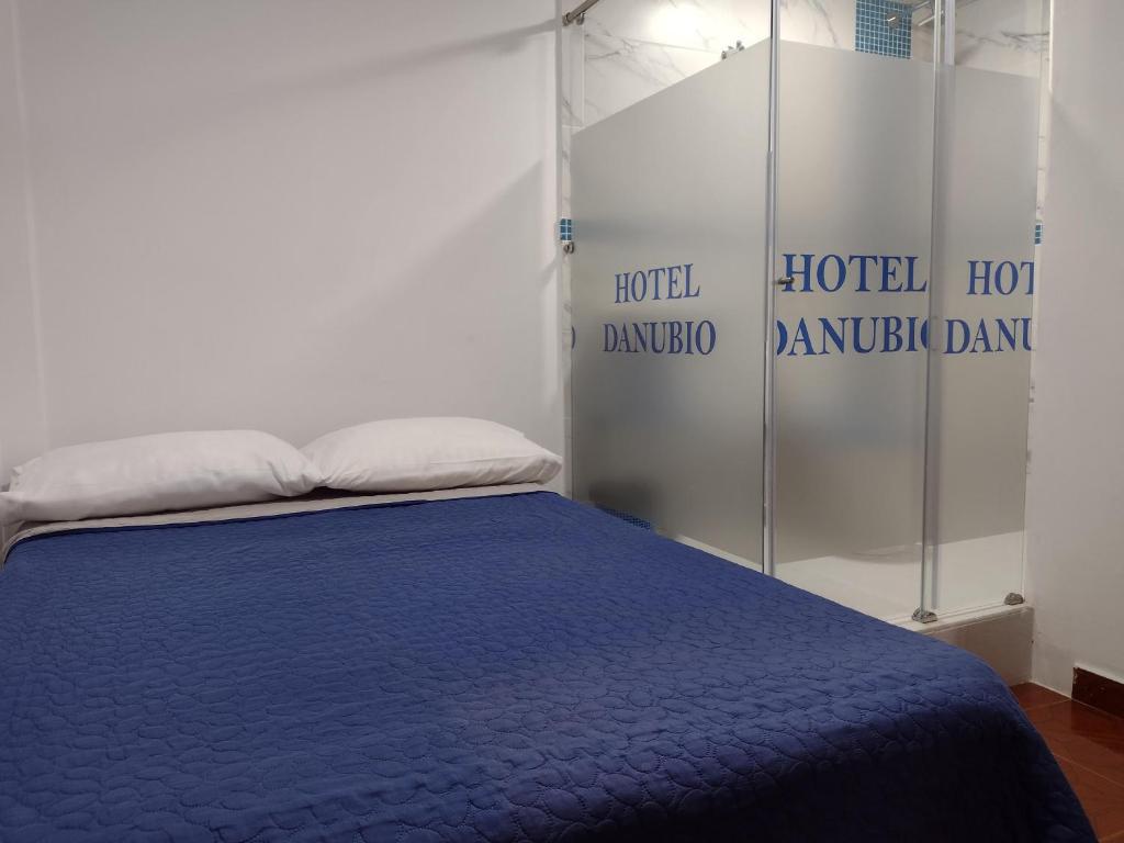 a bedroom with a bed with a blue blanket at HOTEL DANUBIO in Bogotá
