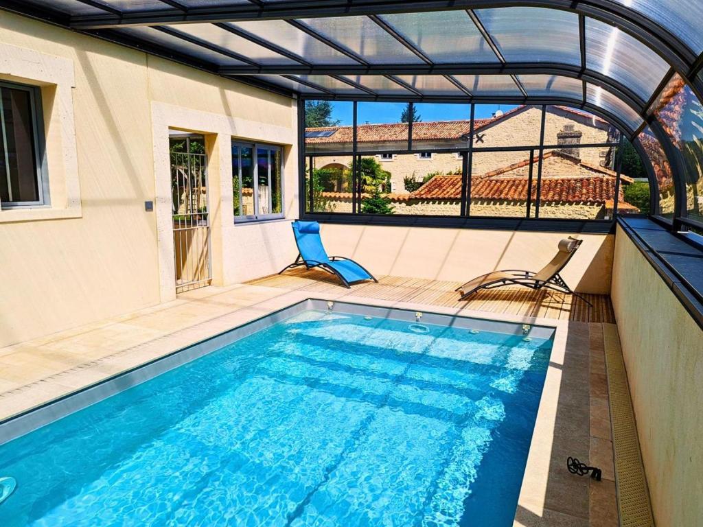 une piscine avec deux chaises à côté d'une maison dans l'établissement Maison Charentaise Rénovée: 3 Ch, Terrasse, Piscine Chauffée, Sauna, Jardin, Équipements Bébé, WiFi - FR-1-653-80, à Salles-de-Barbezieux