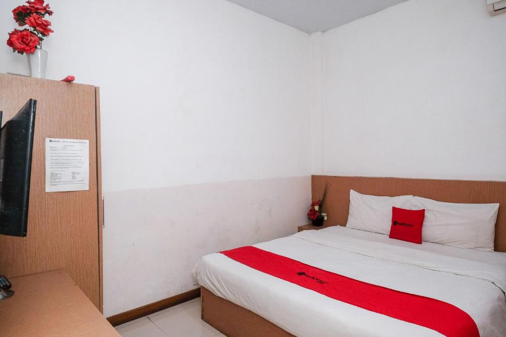 a bedroom with a bed with a red blanket at RedDoorz @ Pengayoman Panakkukang 2 in Makassar