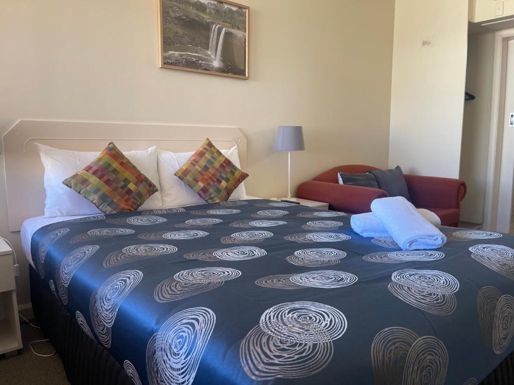 a bedroom with a large bed with a blue blanket at Grand Central Motel in Mount Gambier