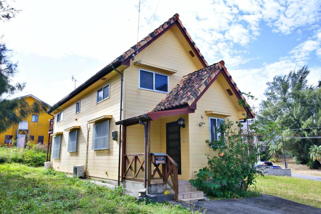 ein kleines gelbes Haus mit braunem Dach in der Unterkunft 川平ハウス in Onna