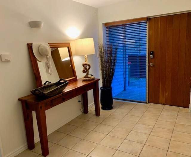 een kamer met een spiegel en een tafel met een lamp bij Luxury Beach Guest House in Papamoa