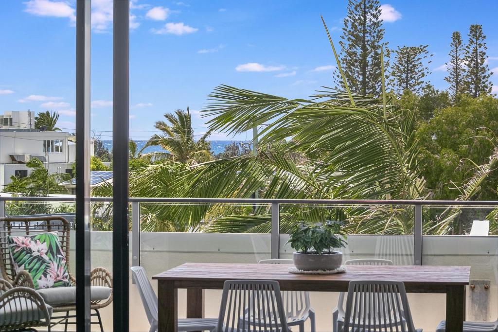 a table and chairs on a balcony with a palm tree at Cabarita Beachside - 1st Floor 2BR Apt by uHoliday in Cabarita Beach