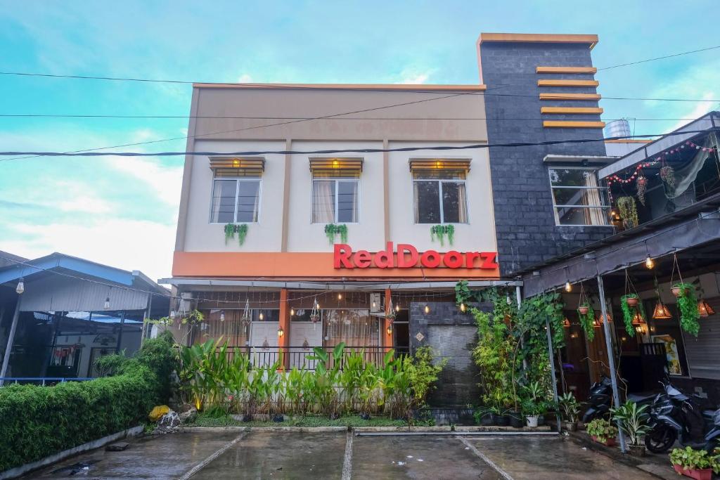 een restaurant met een rood bord op een gebouw bij RedDoorz near Jalan Wolter Monginsidi Manado in Manado