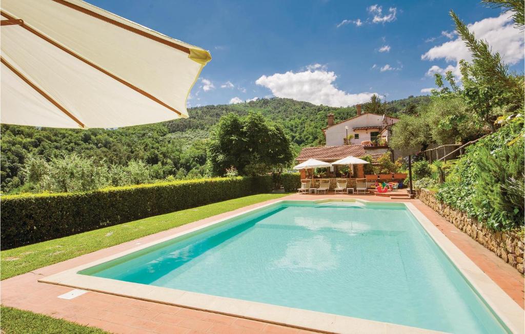 a swimming pool with an umbrella next to a house at Casa Alice in Cireglio