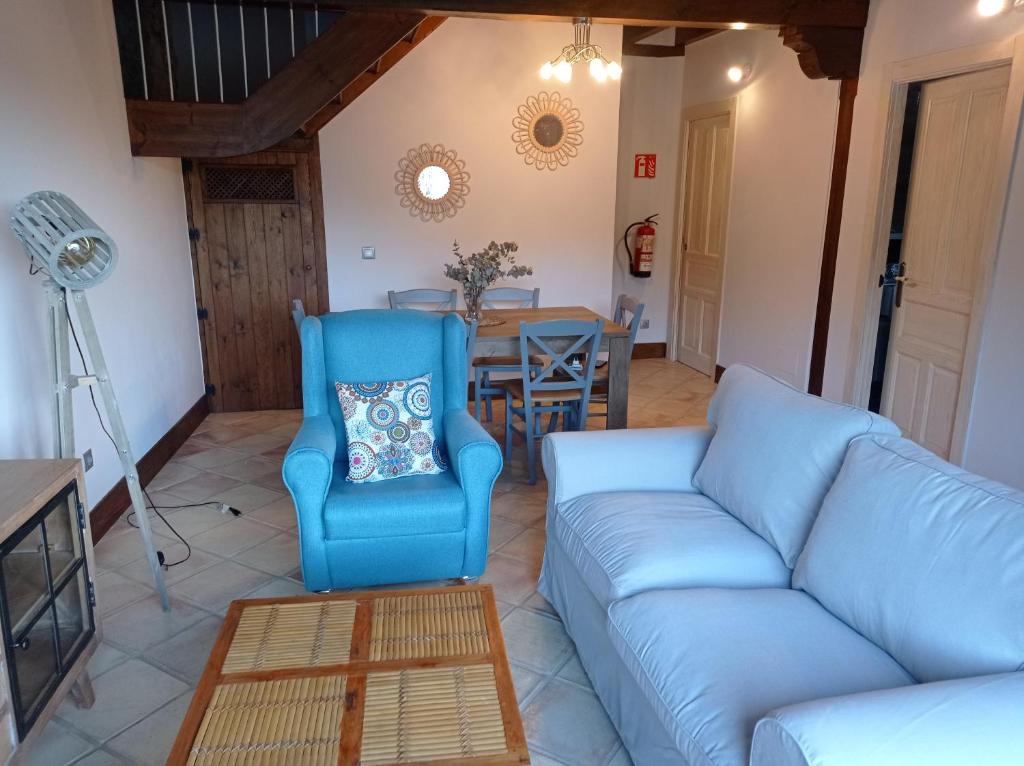 uma sala de estar com um sofá azul e uma mesa em Casa con encanto en La Hayuela, situada a 5 min de Comillas em Udias
