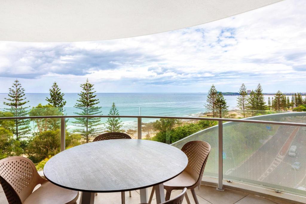 a table and chairs on a balcony with a view of the ocean at Breeze 801 in Mooloolaba