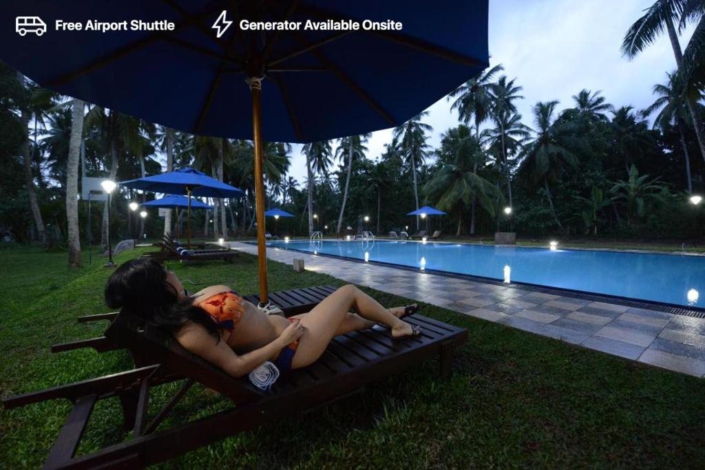 une femme assise sur un banc à côté d'une piscine dans l'établissement Oreeka - Katunayake Airport Transit Hotels, à Katunayake