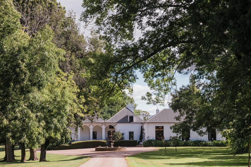 ein weißes Haus mit Bäumen davor in der Unterkunft Quamby Estate in Hagley