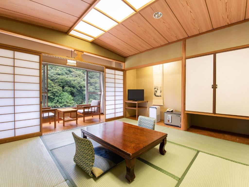 sala de estar con mesa de madera y sillas en Shin Kabakawa Kanko Hotel en Takamatsu
