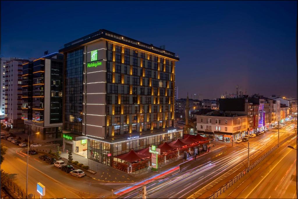 a tall building on a city street at night at Holiday Inn Kayseri - Duvenonu, an IHG Hotel in Kayseri