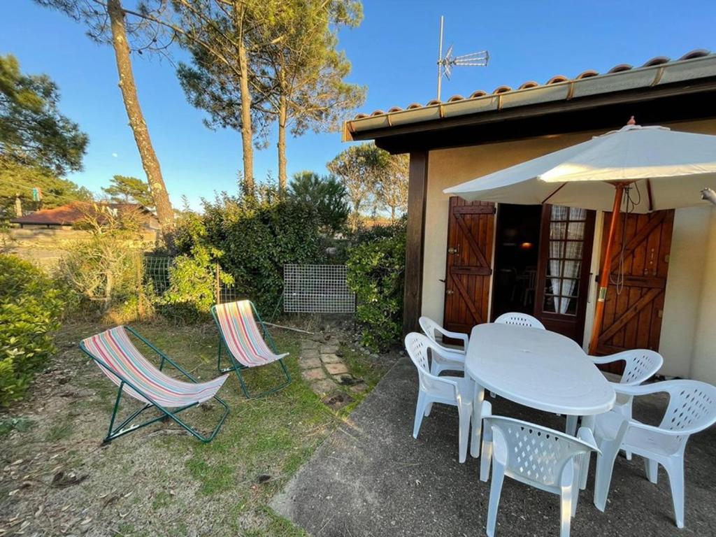 eine Terrasse mit einem Tisch, Stühlen und einem Sonnenschirm in der Unterkunft Maison Capbreton, 3 pièces, 5 personnes - FR-1-413-120 in Capbreton