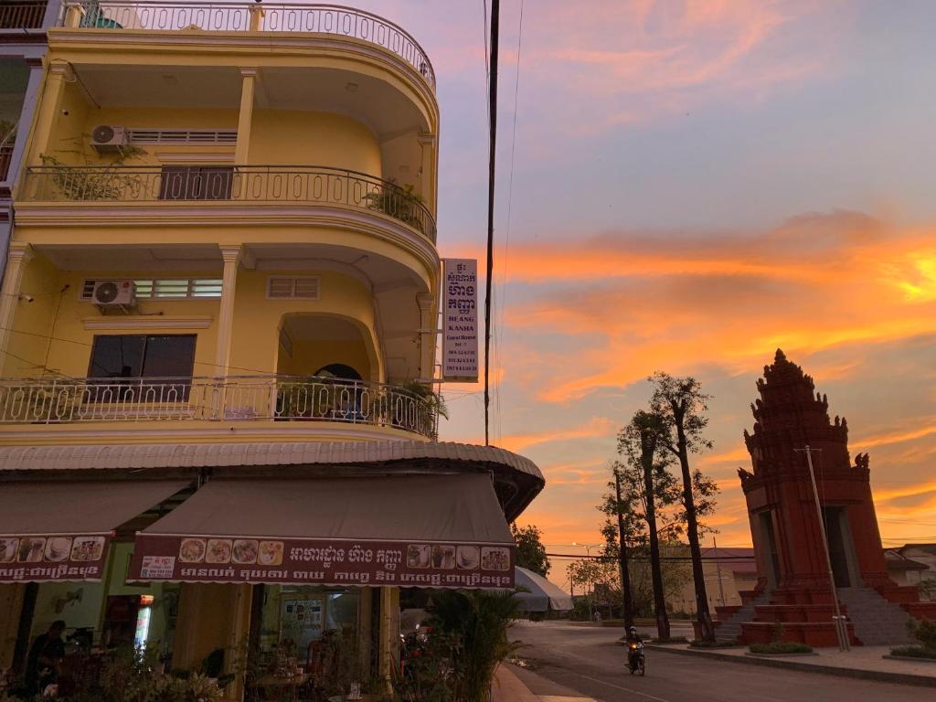 HeangKanha GuestHouse في Phumĭ Chŏng Kaôh: مبنى فيه برج ساعه امام غروب الشمس