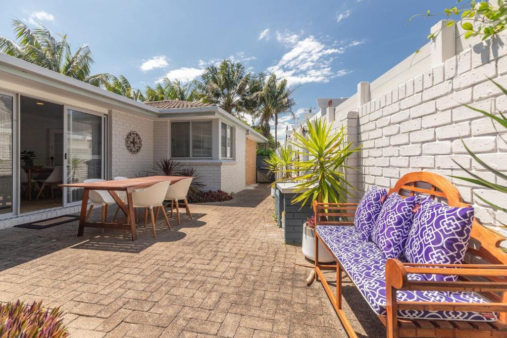 a patio with a table and chairs and a house at The Reef in Boomerang Beach