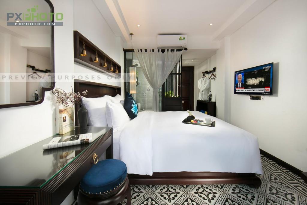 a bedroom with a large white bed and a television at Carillon Boutique Hotel in Hanoi