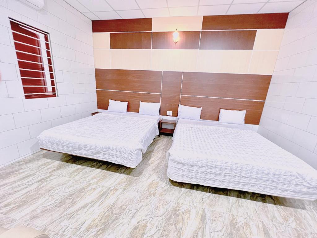 two beds in a room with white walls at Khách sạn Ngọc Bích 2 in Thôn Tân Hội