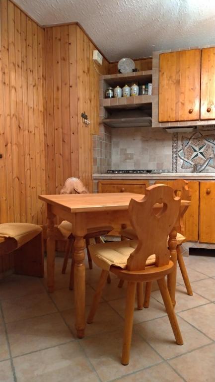 a kitchen with a wooden table and a wooden chair at Casa vacanza a 1km dalla funivia in Chiesa in Valmalenco