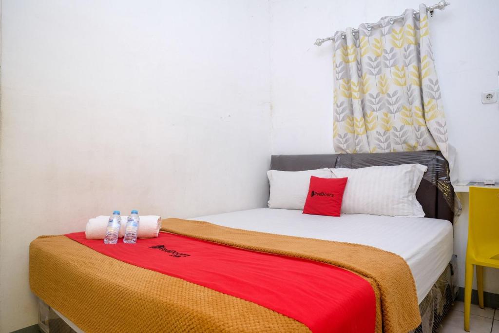 a small bedroom with a bed with a red blanket at RedDoorz near Politeknik Manado in Paniki