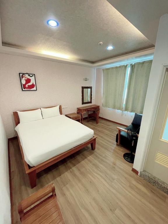 a bedroom with a large white bed and a desk at Blue Sea Inn in Eluan