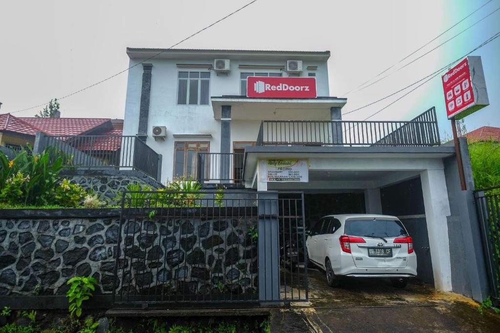 um carro estacionado numa garagem em frente a um edifício em RedDoorz near De La Salle Manado em Manado