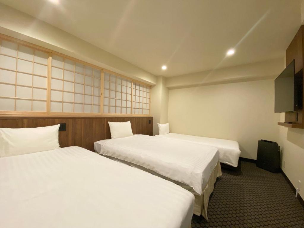 a hotel room with two beds and a flat screen tv at Kadoya Hotel in Tokyo