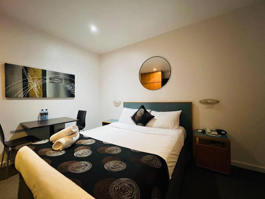 a hotel room with a large bed and a mirror at city ex hotel ensuite room in city 408 in Adelaide