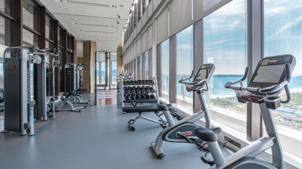 um ginásio com passadeiras e bicicletas ergométricas em frente às janelas em Crowne Plaza Sanya Haitang Bay Resort, an IHG Hotel em Sanya