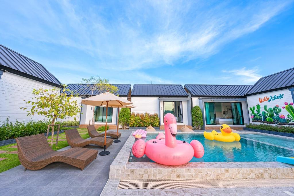 Un patio trasero con piscina con inflables y una casa. en วิลล่ากันติ (Bed and Breakfast), en Bang Sare