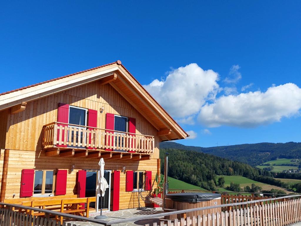 Blockhütte mit bunten Fenstern und Balkon in der Unterkunft Bergchalet am Waldrand - Pool, Sauna & Kamin in Pöllauberg