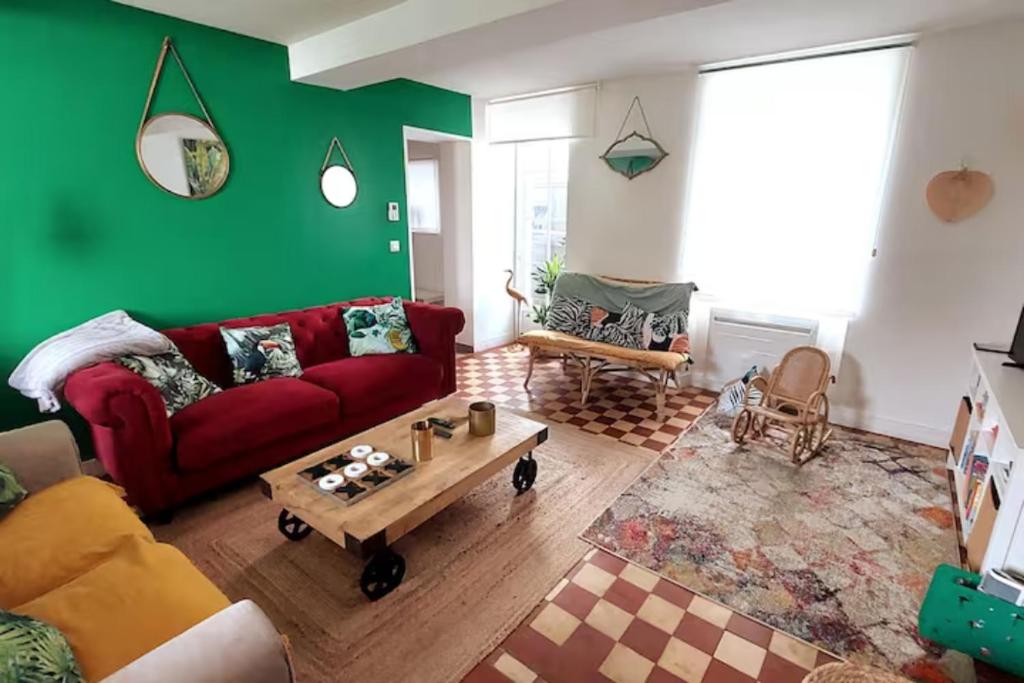 a living room with a red couch and a green wall at Maison avec jardin, près plages du débarquement, table ping pong, à 800 m d' Omaha beach adaptée jeunes enfants in Vierville-sur-Mer