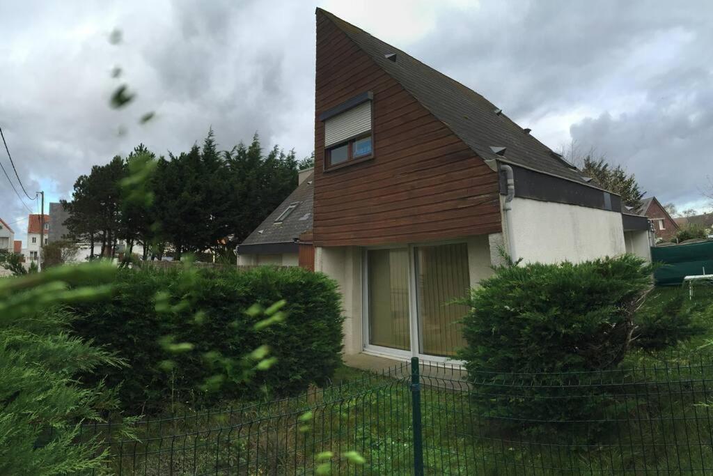 une maison avec un toit marron et une clôture dans l'établissement Cottage de la mer, au Crotoy
