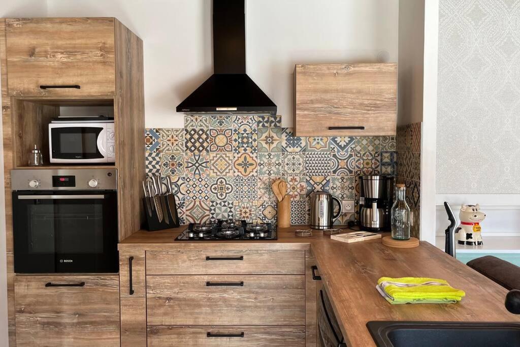 a kitchen with wooden cabinets and a stove top oven at La Reinette du Verger 9 d&#39;Arry 1 in Arry