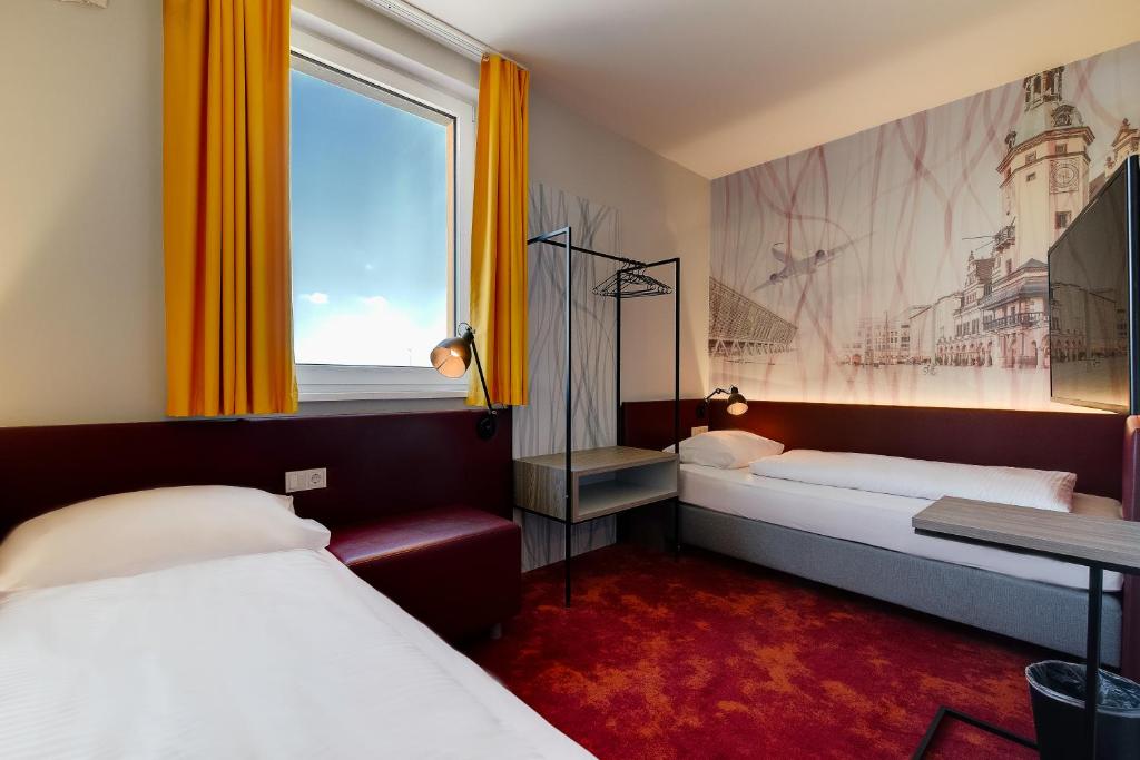a hotel room with two beds and a window at Campanile Leipzig Halle Airport in Leipzig