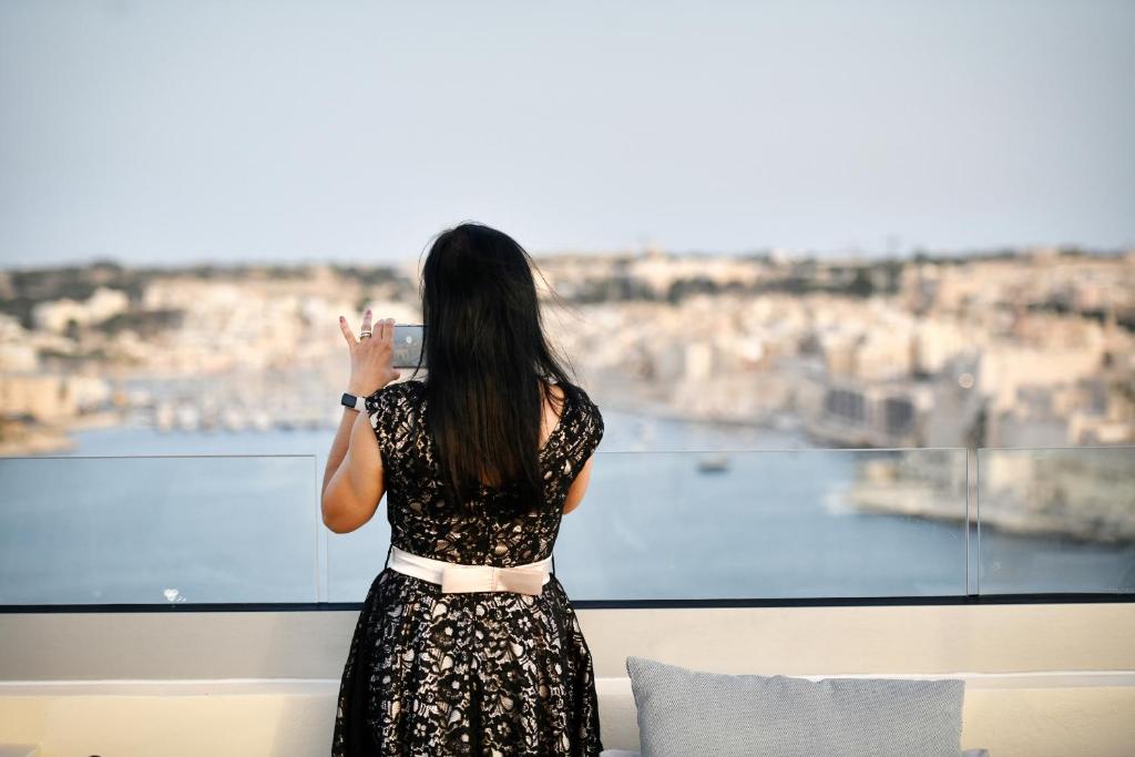 una mujer tomando una foto de la ciudad desde una ventana en Palazzo Ignazio, en La Valeta