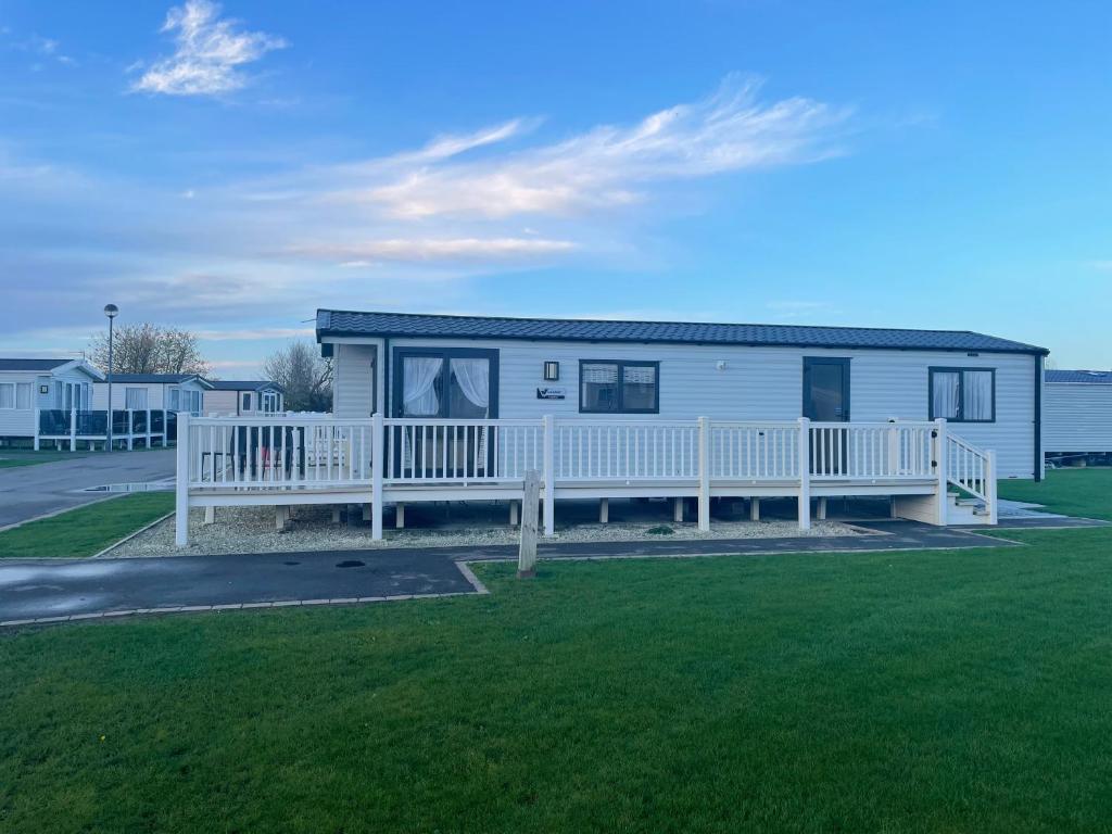 a white house with a porch and a white fence at Golden Sands Retreat in Mablethorpe