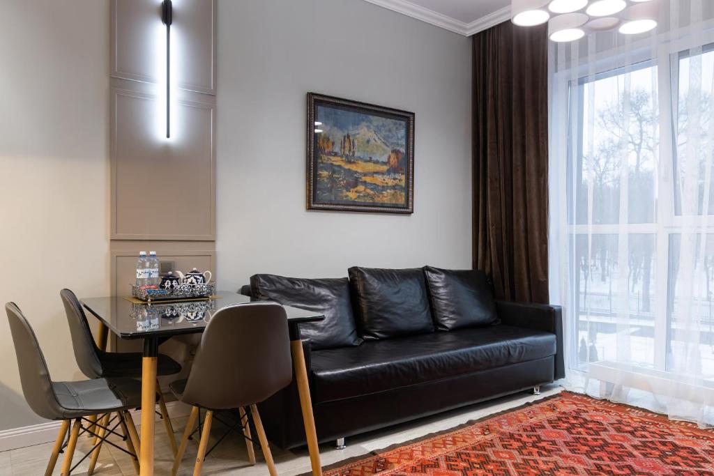 Una sala de estar con un sofá de cuero negro y una mesa. en Central Park View, en Almaty