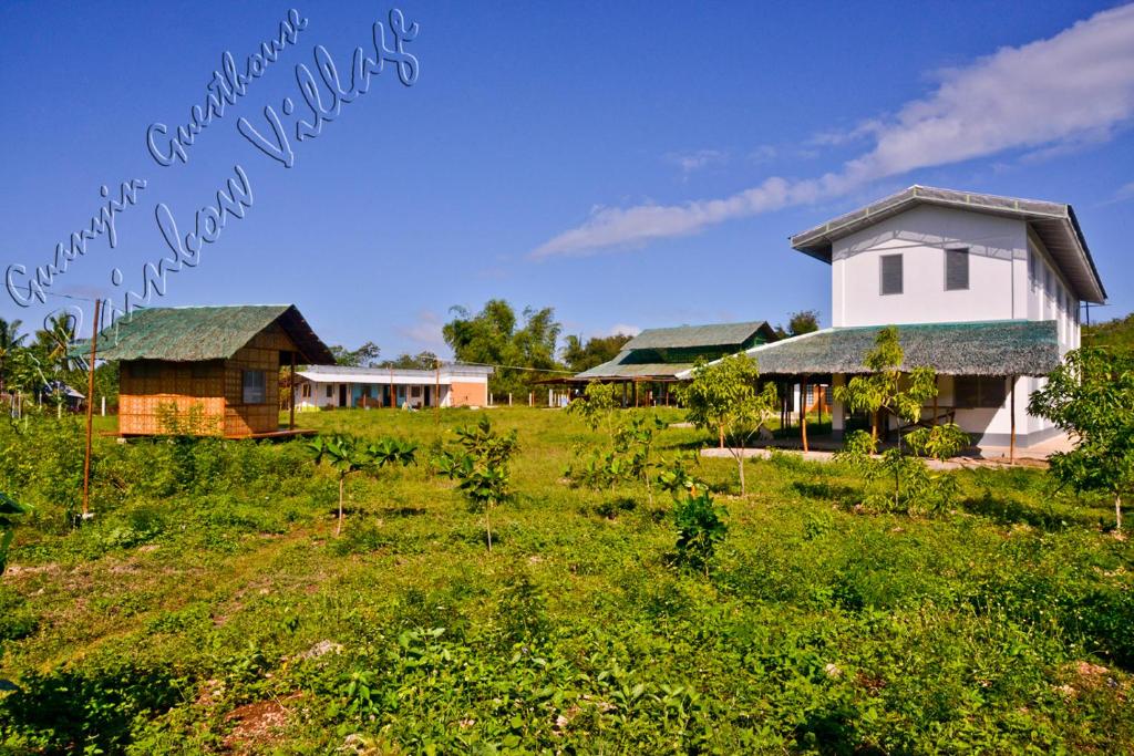 a group of houses in a field of grass at Guanyin Guesthouse at Rainbow Village in Maricaban