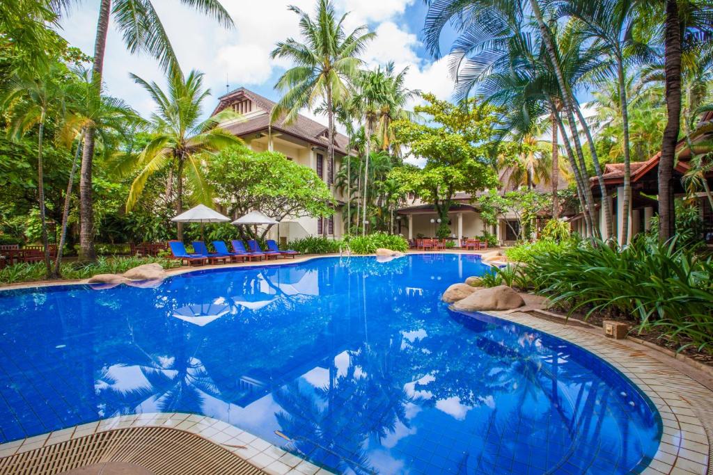 a swimming pool in front of a house with palm trees at Settha Palace Hotel in Vientiane