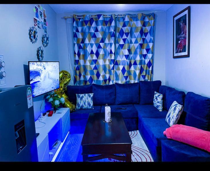a blue living room with a blue couch and a table at one bedroom airbnb with swimmingpool, kiambu road in Kiambu
